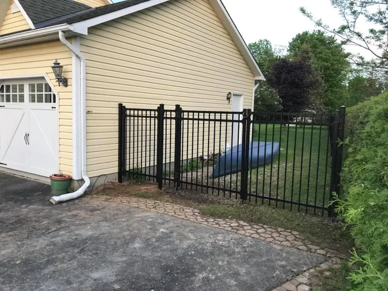 Black aluminum double gate closing a paving stone driveway