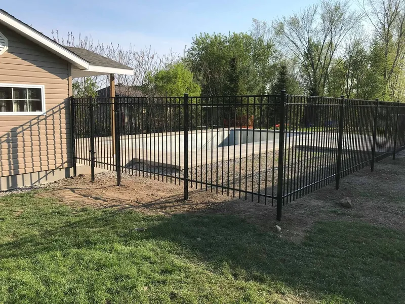 Black aluminum fence forming the enclosure around an in-ground pool