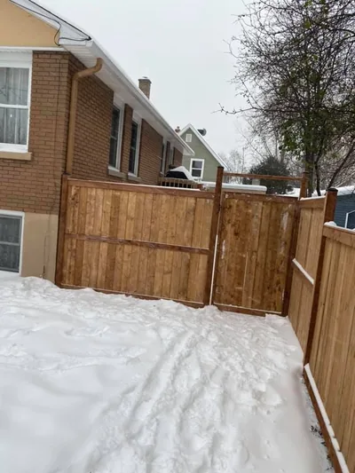 Wood gate and fence installed in winter, snow on the ground
