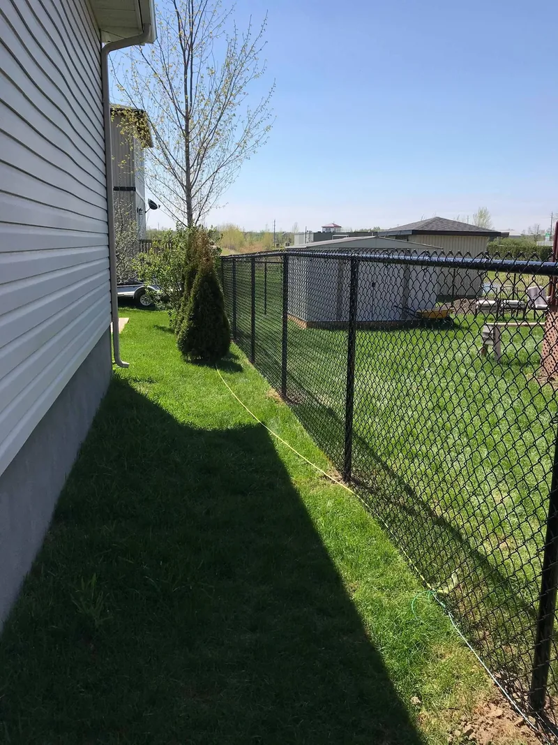 Black chain link fence running along the side of a house