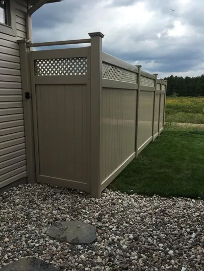 Beige PVC gate with lattice top, on a gravel bed