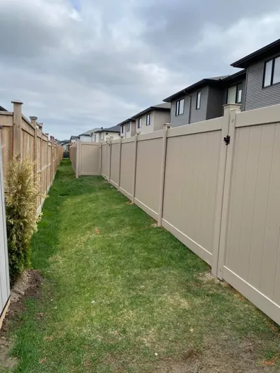 Beige PVC fence on both sides of a narrow yard corridor