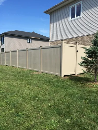 Beige PVC fence running along the side of a house