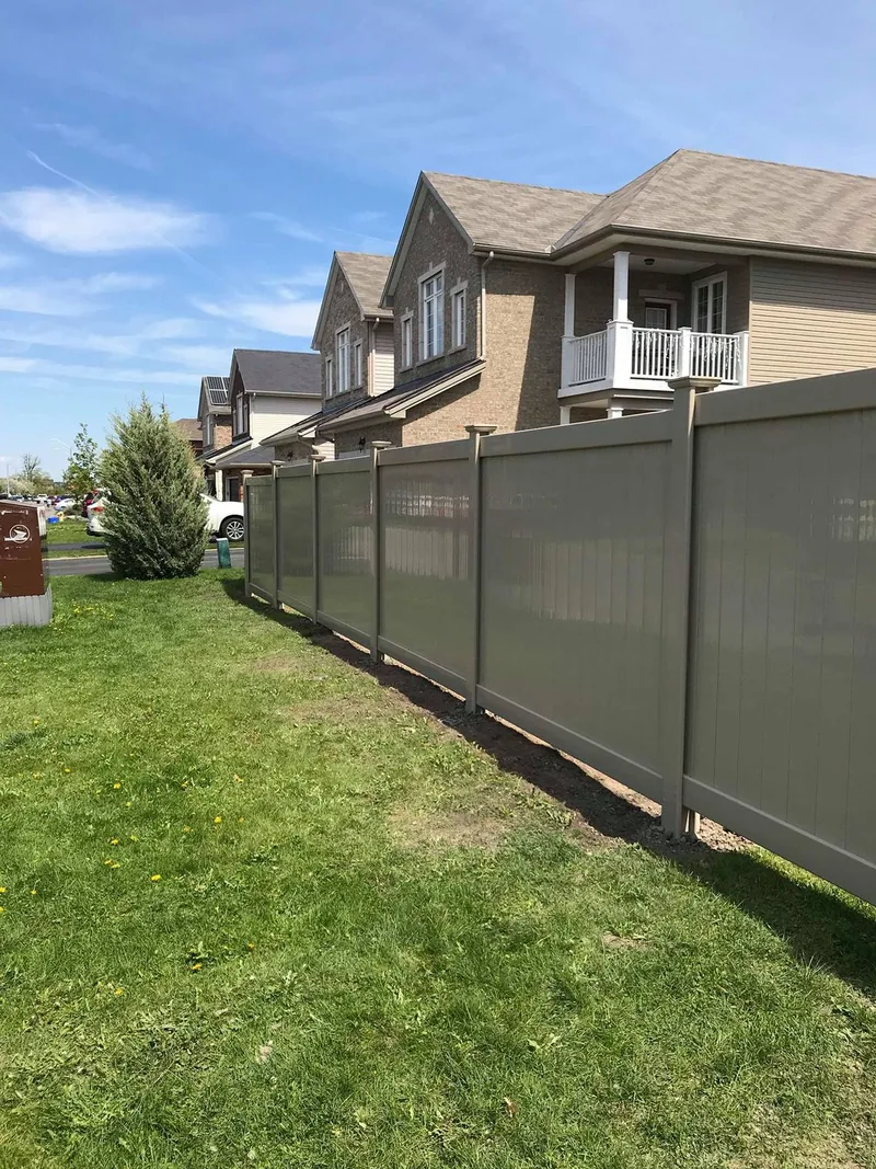 Long beige PVC fence between two properties