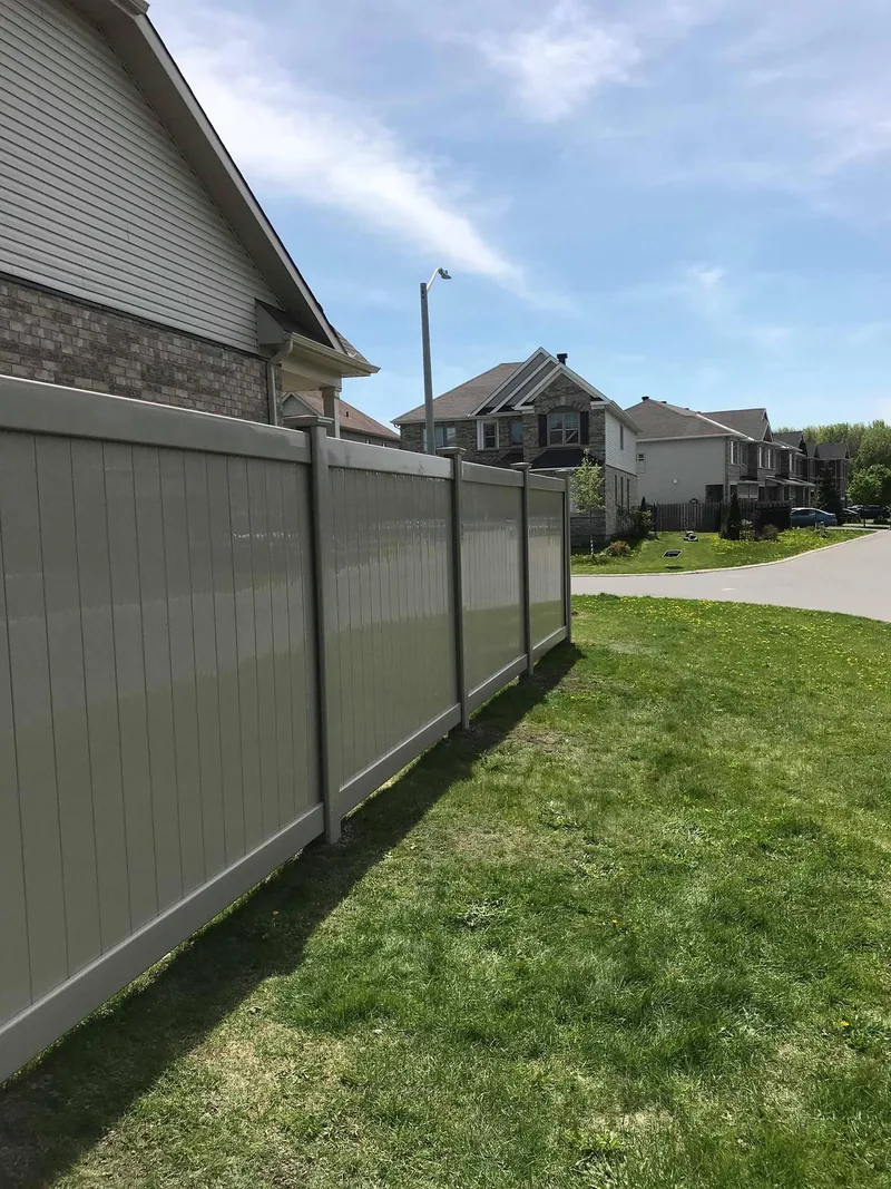 Beige PVC fence running from a house out to the street