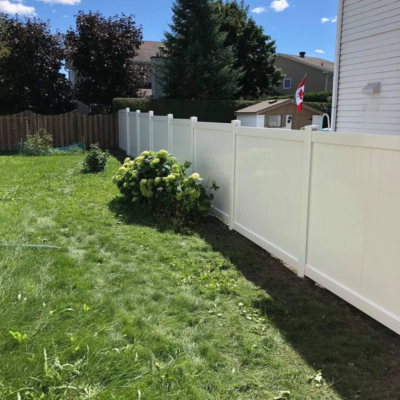 White PVC fence with a hedge and landscaping alongside