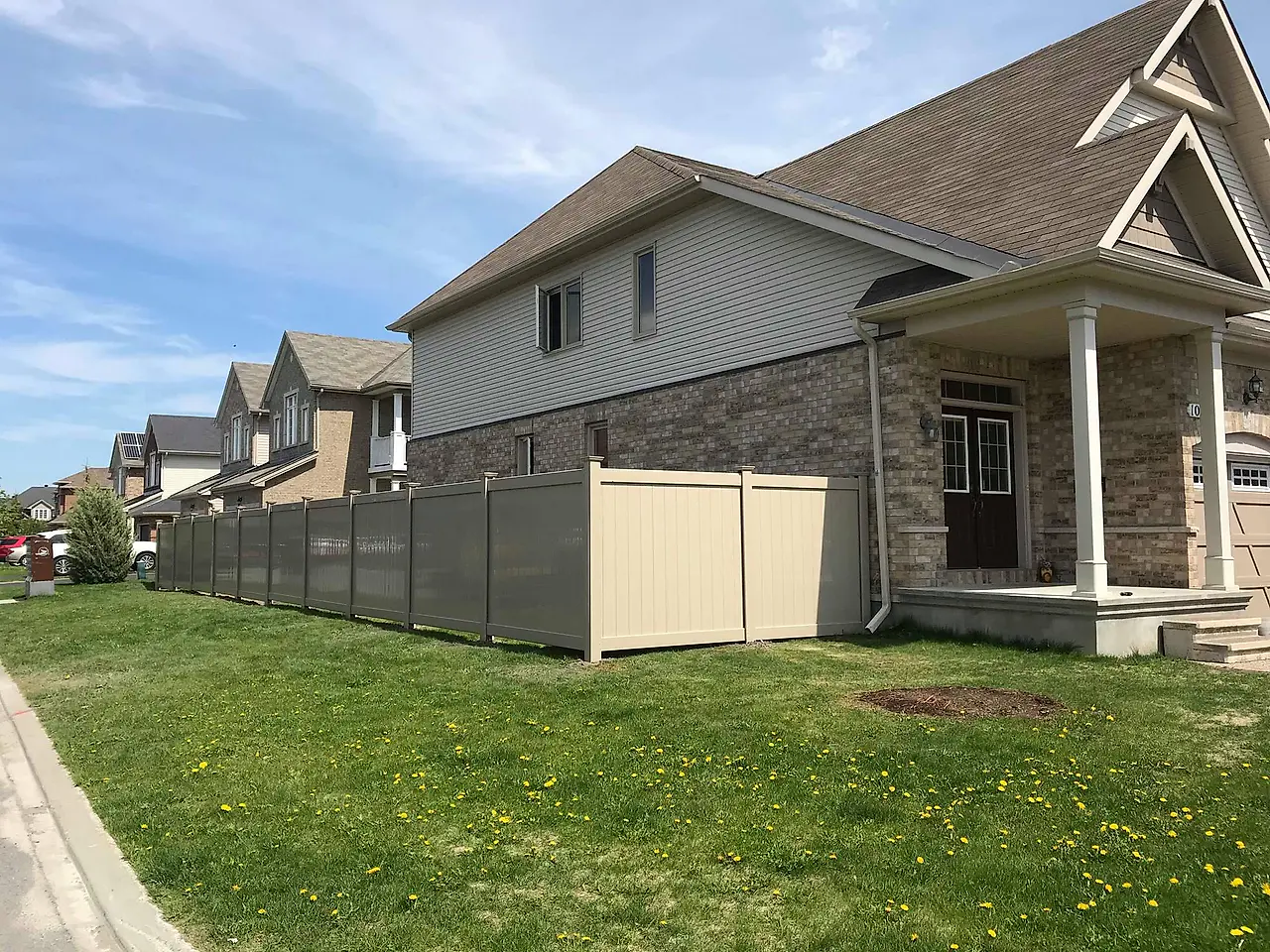 Two tone PVC fence installed by Clôtures DKA along a brick house