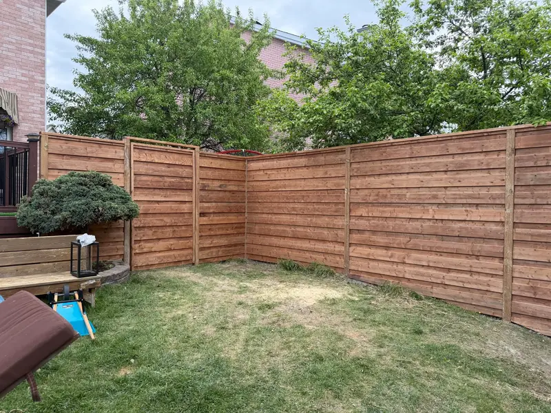 Horizontal slat wood fence turning the corner of a yard, with a clean return