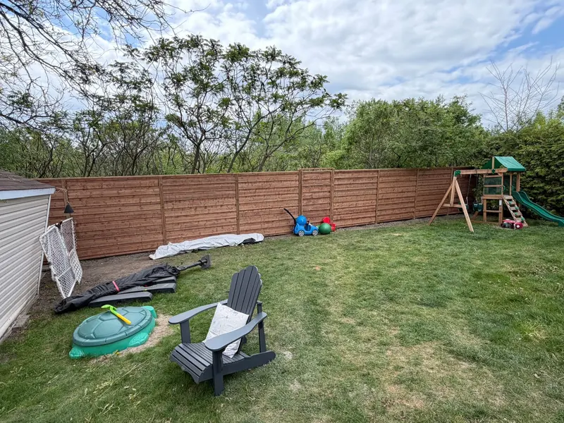 Long run of horizontal slat wood fence along the back of a yard