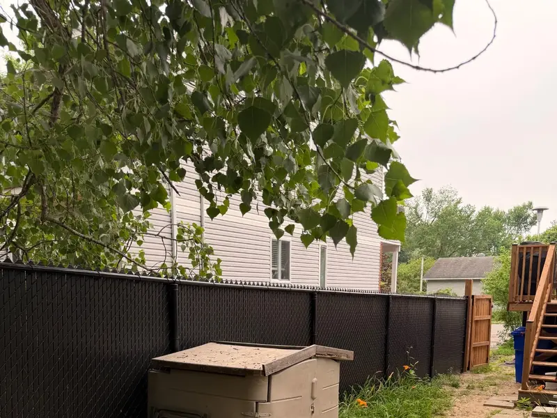 Black chain link fence with privacy slats and a wood gate