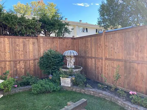 Stained wood fence at the corner of a backyard